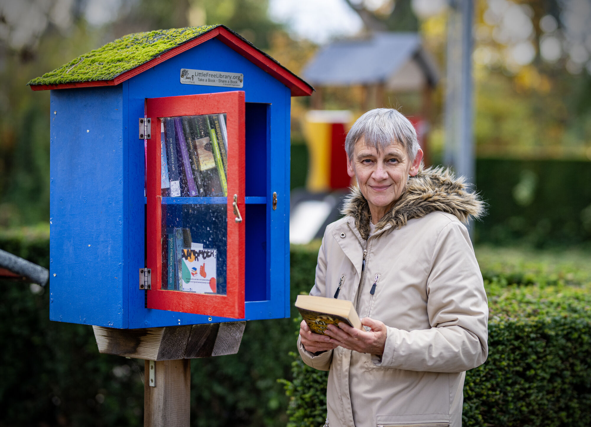 Rita haalt een boek uit het boekenruilkastje in Breendonk